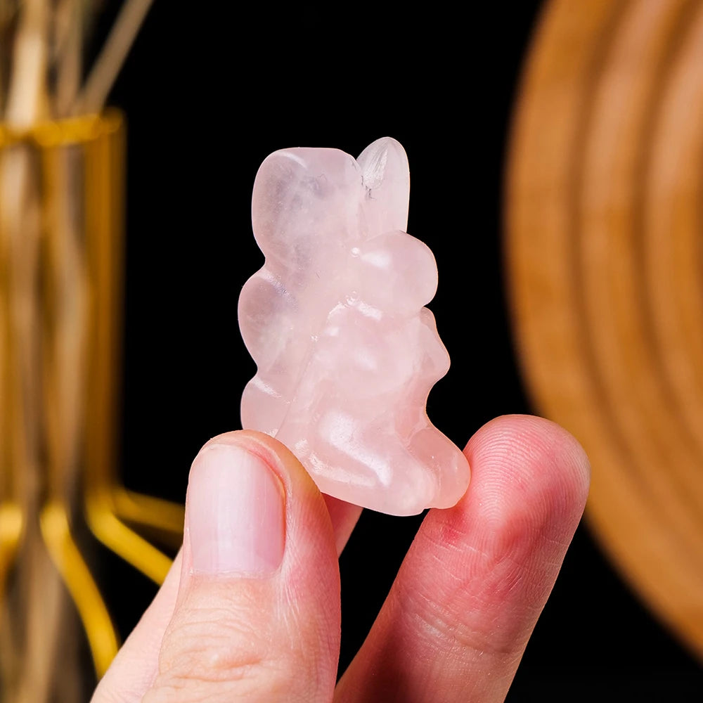 Close-up of hand-carved rose quartz angel figurine, emphasizing smooth texture and angelic features